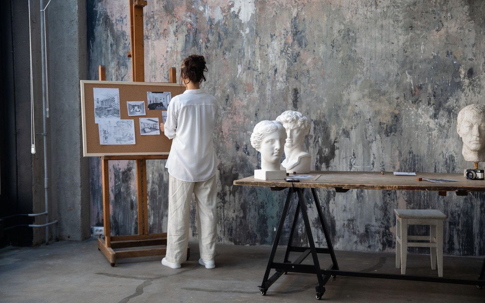 A wall of framed académie charcoal drawings of adult male figures in constrained poses, studio setting